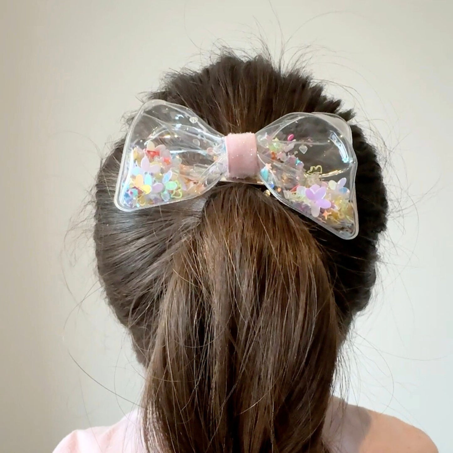 Clear hair bow filled with colorful confetti, perfect for adding sparkle and fun to party outfits or everyday looks.