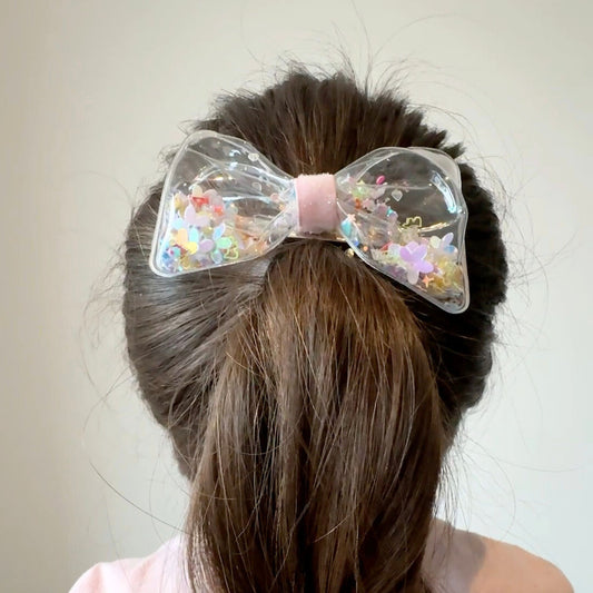 Clear hair bow filled with colorful confetti, perfect for adding sparkle and fun to party outfits or everyday looks.